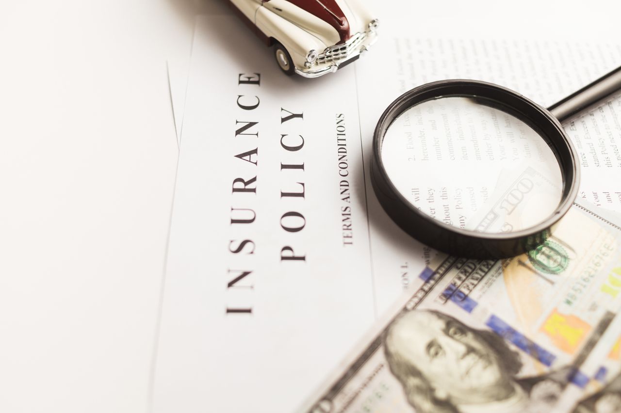Services Close-up image of an insurance policy with a magnifying glass, money, and toy car.