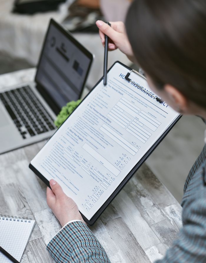 Crafting Captivating Headlines: Your awesome post title goes here An adult reviews a home insurance policy document at a desk with a pen and laptop.