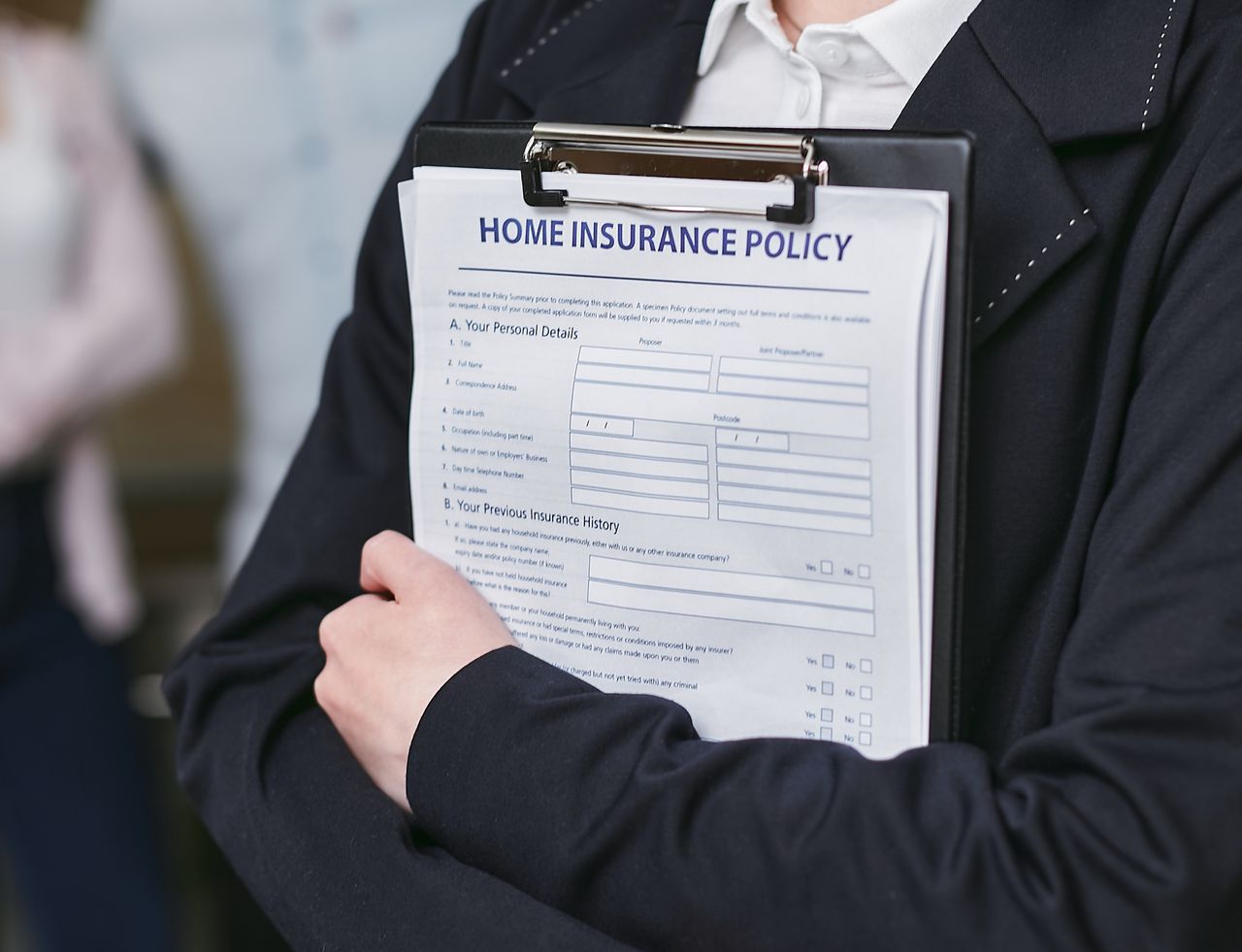 Services Close-up of a person holding a home insurance policy on a clipboard, captured indoors.