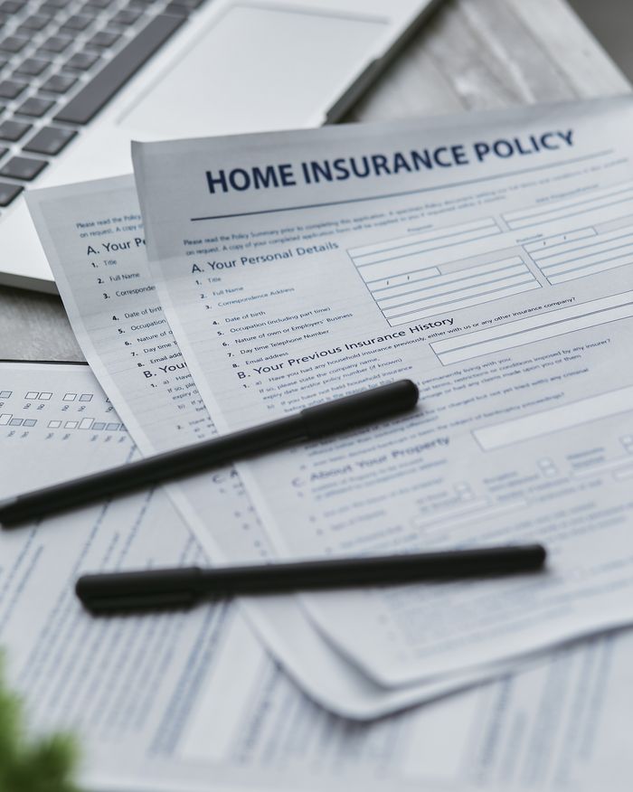 Services Close-up of home insurance documents with a laptop for financial planning.